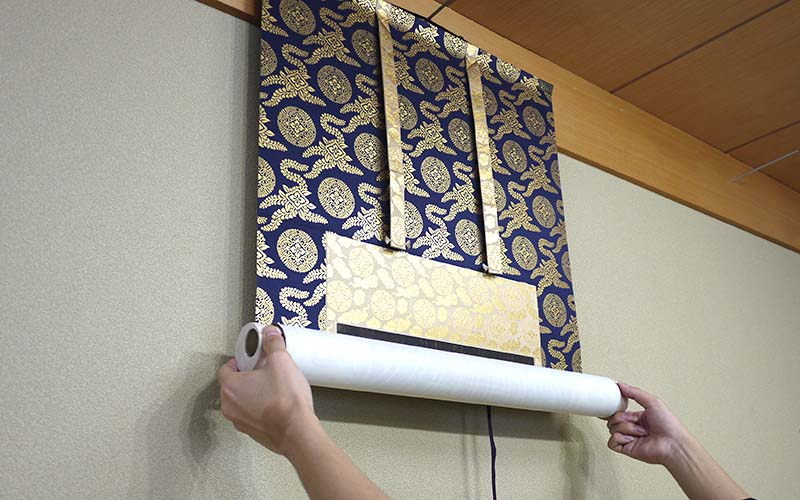 掛軸の両端を持つ
